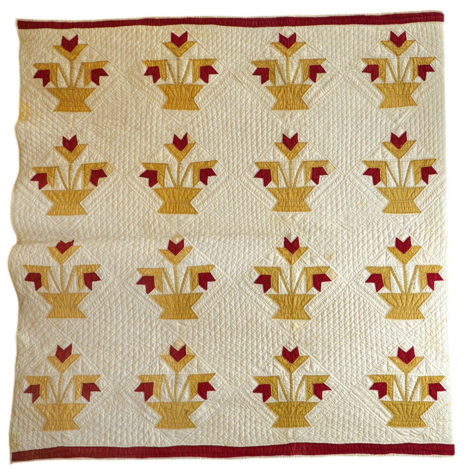 An early 20th century American ‘Carolina Lily’ quilt, worked on a cream cotton in two colours, sand and red patchwork creating motifs of large angular abstracted vases of flowers, the quilt then bordered with red, 185cm